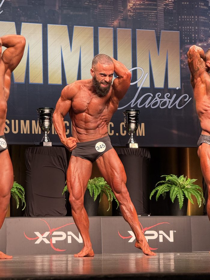 Kareem on stage at a bodybuilding competition, front pose